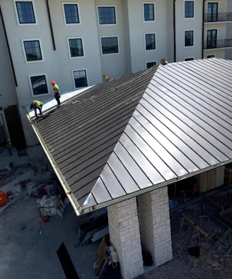 Crew installing standing seam metal roof panels on a commercial project in Odessa